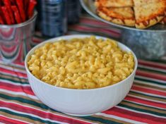 a bowl of macaroni and cheese on a table with other food items in the background