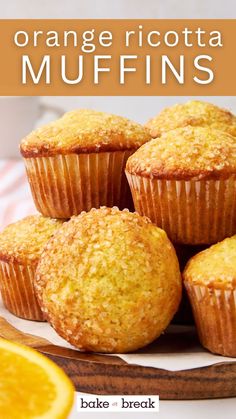 orange ricotta muffins on a cutting board with an orange in the background