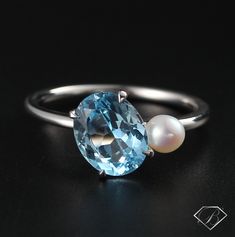 a ring with an aqua blue topazte and a white pearl on the side