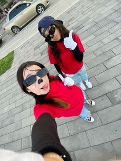 two girls in sunglasses are standing on the sidewalk