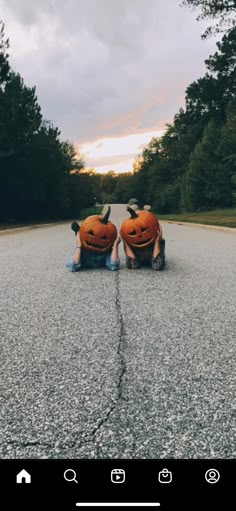 two people riding on skateboards down a road with pumpkins carved into the sides