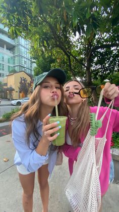 two girls drinking coffee and posing for the camera with one holding a straw in her hand