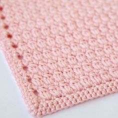 a pink crocheted blanket laying on top of a white table