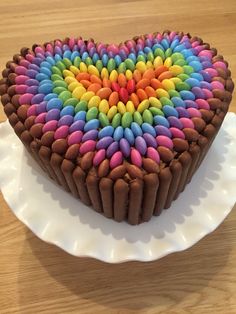 a heart shaped cake with chocolate frosting and rainbow colored icing on it's side