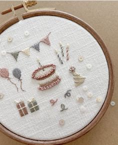 a close up of a embroidery on a hoop with buttons and pins attached to it