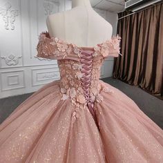 a pink ball gown with flowers on the skirt and off the shoulder, is displayed in front of a mannequin