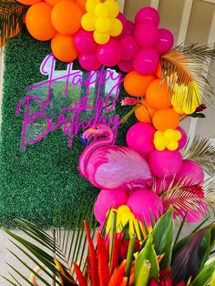 a flamingo themed birthday party with balloons, flowers and greenery on the wall