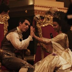 a man and woman sitting on top of a red chair in front of a mirror