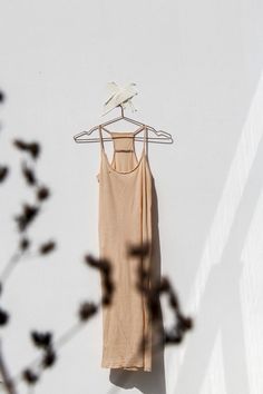 a tan tank top hanging on a white wall