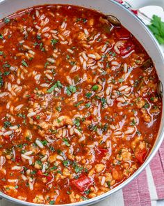 a large pot filled with pasta and sauce on top of a red and white checkered table cloth