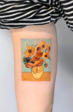 a woman's arm with a vase filled with sunflowers on top of it