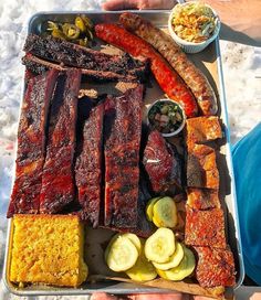 a bbq platter with ribs, pickles, and other foods on it