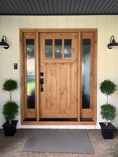 a front door with two potted plants on the side