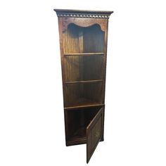 a tall wooden bookcase with an open door on one side and a drawer on the other