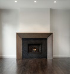 an empty room with a fire place in the center and wood floors on both sides