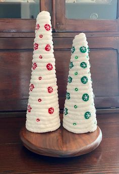 two white christmas trees sitting on top of a wooden table