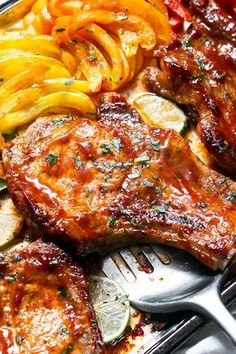 grilled pork chops and sliced vegetables on a tray with fork, knife and spoon