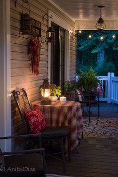 the porch is lit up with lanterns and candles on it, along with an outdoor dining table