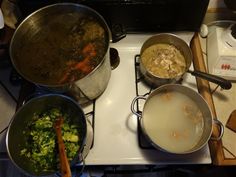 several pots and pans are on the stove top with food being cooked in them