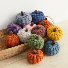 small knitted pumpkins sitting on top of a wooden tray