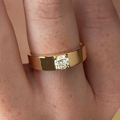 a woman's hand with a gold ring on it and a diamond in the middle