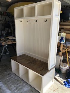 a wooden bench sitting inside of a garage next to a shelf with hooks on it