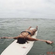 a woman laying on a surfboard in the ocean