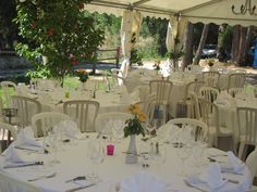 tables and chairs are set up for an outdoor wedding reception under a tented area