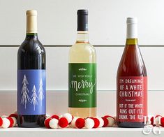 three bottles of wine sitting next to each other on a table with red and white pom - poms