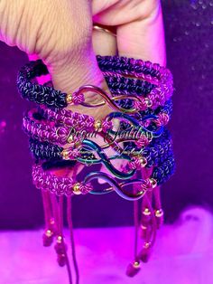 a person is holding several bracelets in purple and blue colors with gold beads on them