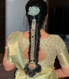 a woman with long hair wearing a green sari and braided up into a ponytail