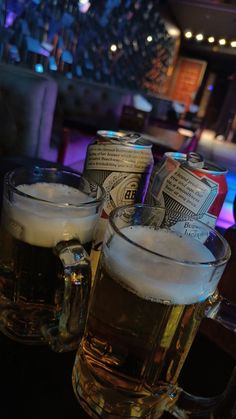 two mugs of beer sitting on top of a table