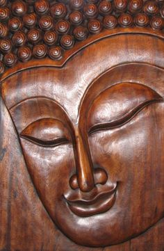 a carved wooden buddha head with eyes closed