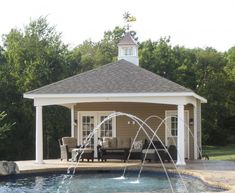 a gazebo with a fountain in the middle of it and chairs on the other side