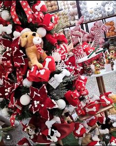 a christmas tree is decorated with red and white ribbons, teddy bears and other holiday decorations