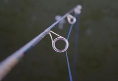 a pair of scissors sitting on top of a blue rope next to another piece of wire