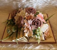 an open book with flowers on top of it