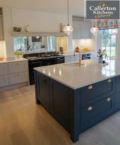 a large kitchen with an island in the middle and two lights hanging from the ceiling