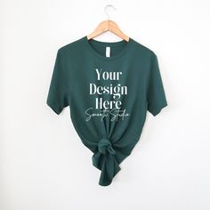 a green t - shirt with the words your design here on it is hanging on a hanger