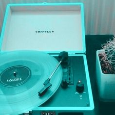 a record player sitting on top of a table next to a cactus