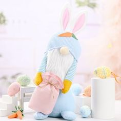 a stuffed rabbit holding a pink bag next to some carrots and an egg on a table