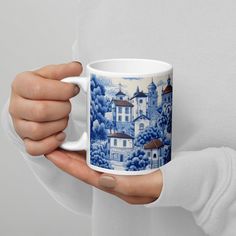 a person holding a coffee mug in their hands with a blue and white design on it