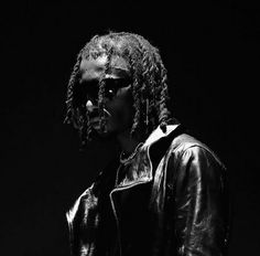 a black and white photo of a man with dreadlocks wearing a leather jacket