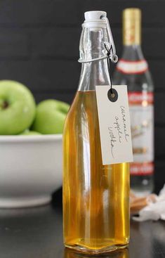 an apple cider is sitting on a table with apples in the background and a note attached to it