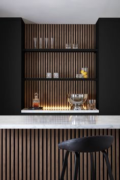 a kitchen with black cabinets and white marble counter tops, along with a bar stool