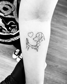 a person with a tattoo on their arm holding a small dog's paw in the shape of a heart