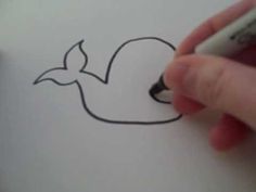 someone is drawing a whale on paper with a marker