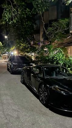 two black sports cars parked on the street at night