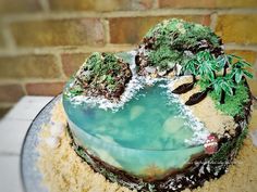 a cake with frosting and trees on it sitting on a table next to a brick wall