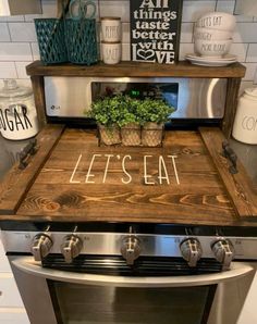 an oven with the words let's eat written on it and a potted plant